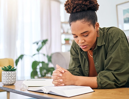 Young woman studying her Bible at a table.