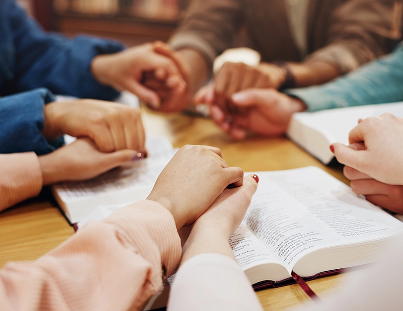 Women's Bible study group holding hands as they pray.